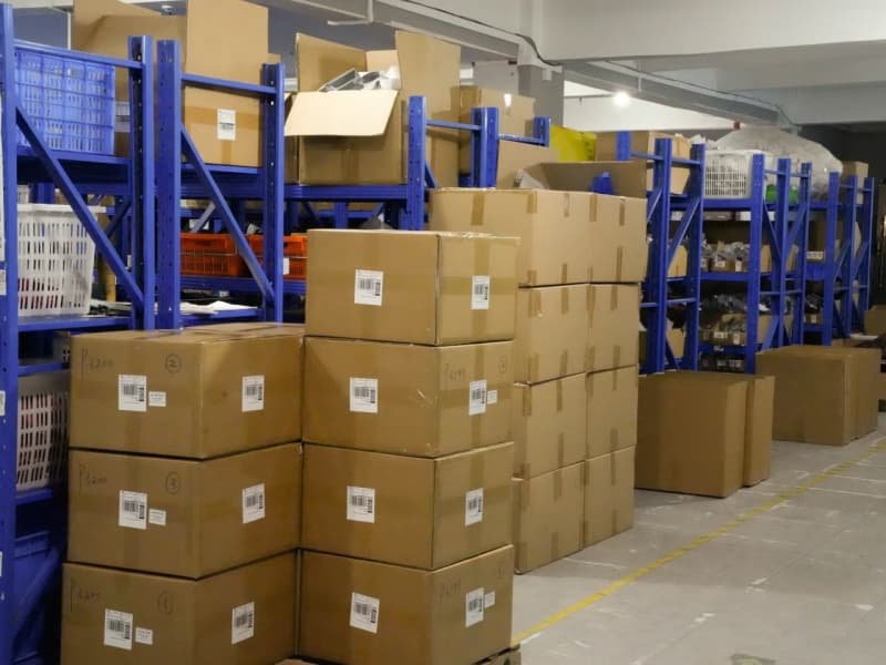 Stacked cardboard boxes and blue storage racks in finished goods warehouse