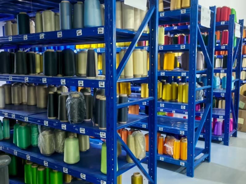 Vibrant colored yarn spools stored in organized industrial shelving units