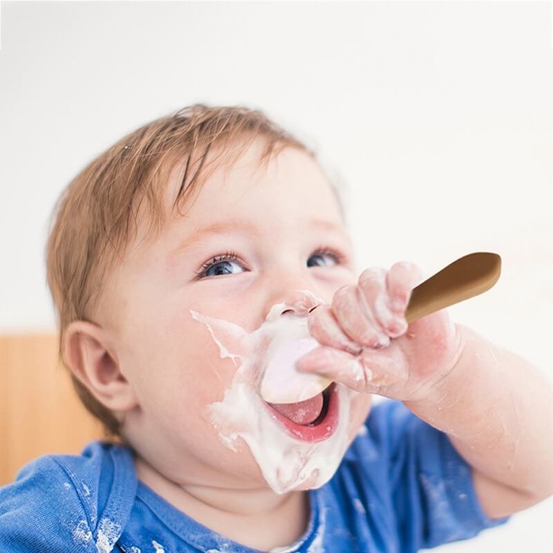 Baby using soft silicone spoon for first feeding